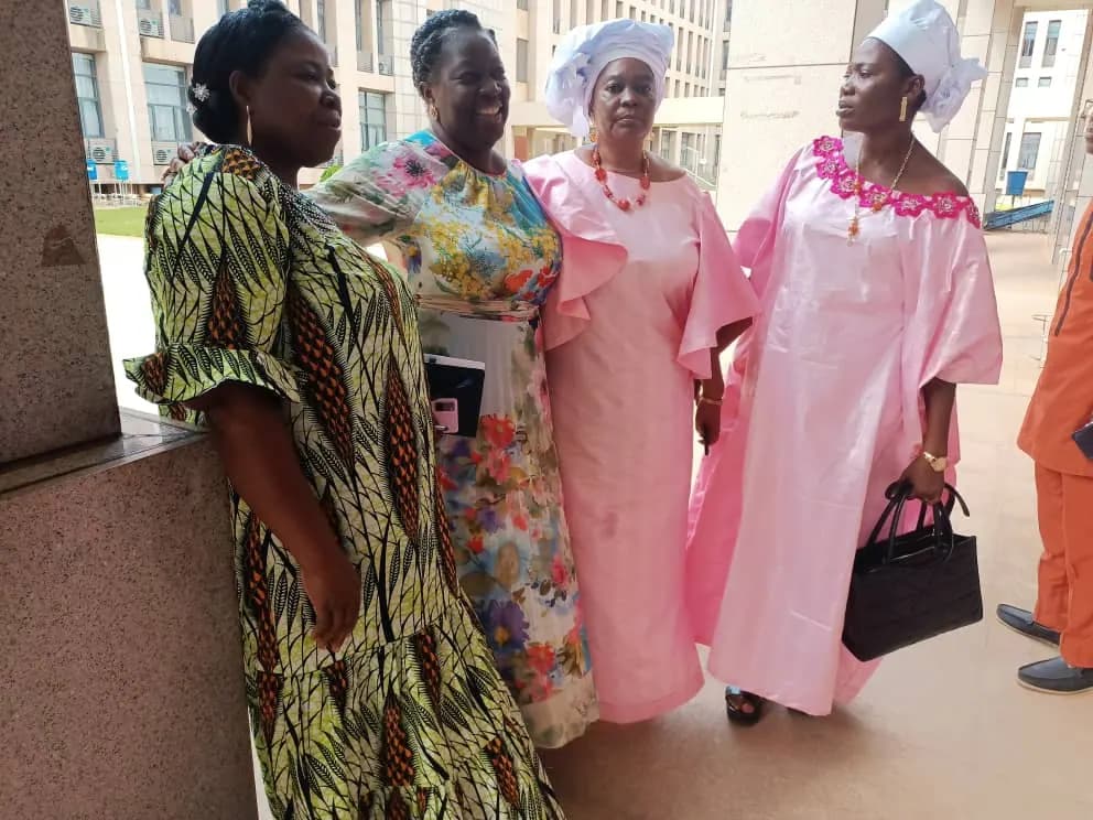 Quatre femmes en tenues roses et en pagne posent ensemble