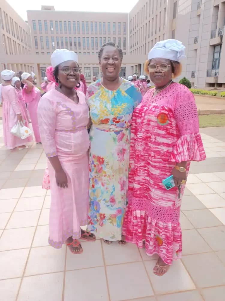 Trois femmes en tenues roses posent sur le parvis d’un bâtiment