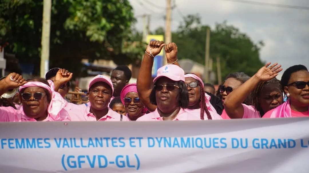 Des marcheuses lèvent le poing derrière la banderole du Groupement des Femmes Vaillantes et Dynamiques du Grand-Lomé