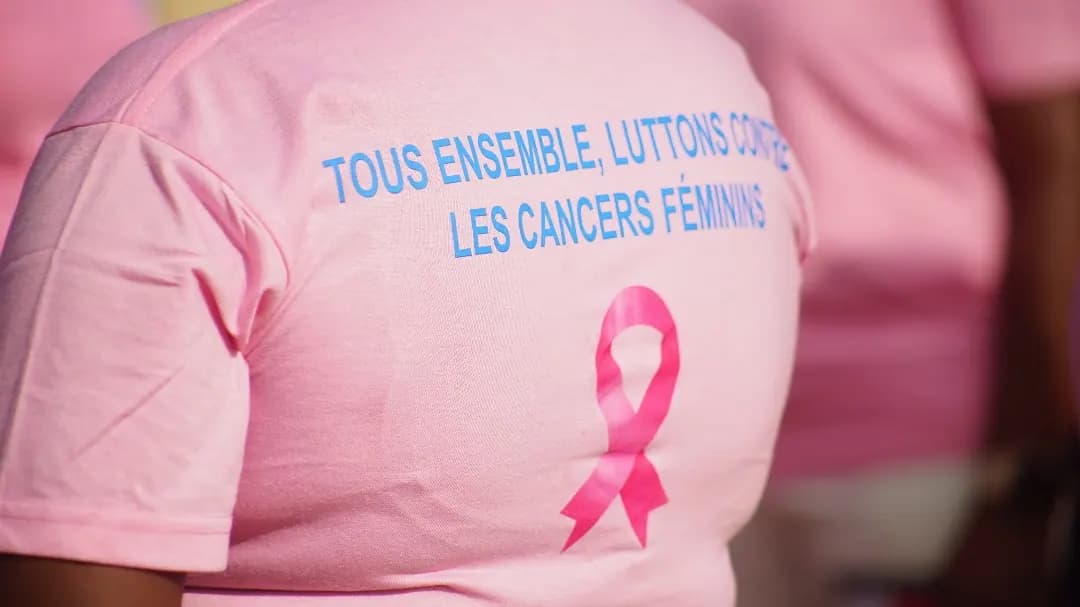 Dos d’un T-shirt rose portant le slogan « Tous ensemble, luttons contre les cancers féminins » et un ruban rose